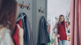 A woman tries on a red garment in a dressing room.