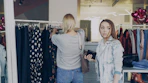 Two women are shopping for clothes in a boutique