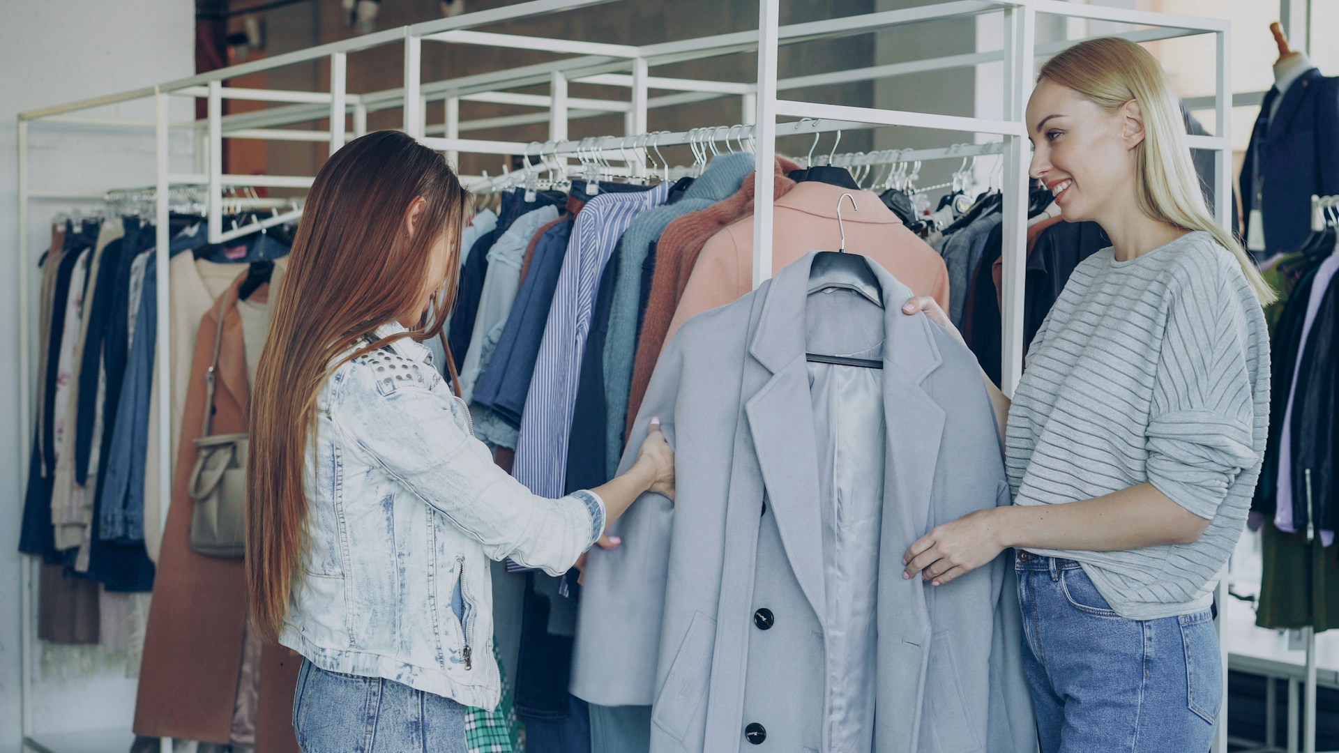 Two women browse clothing racks in a boutique.