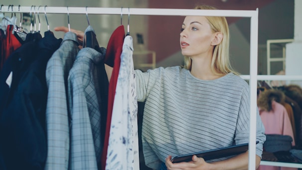 A woman chooses clothes from a rack.