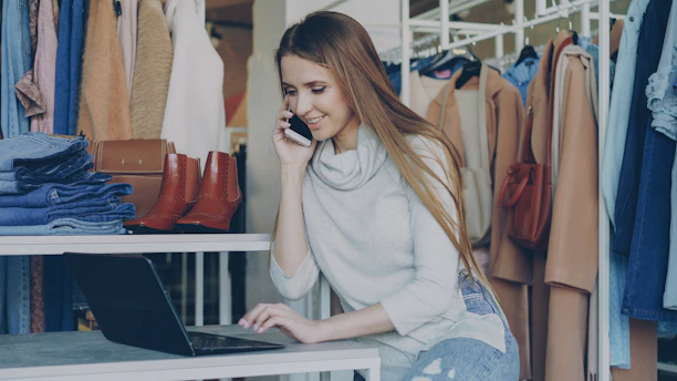 Woman talks on the phone while using a laptop.