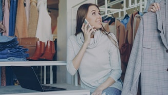 Woman is on the phone while looking at clothes.