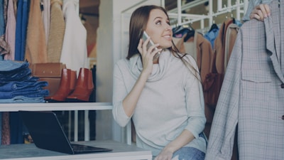 Woman is on the phone while looking at clothes.