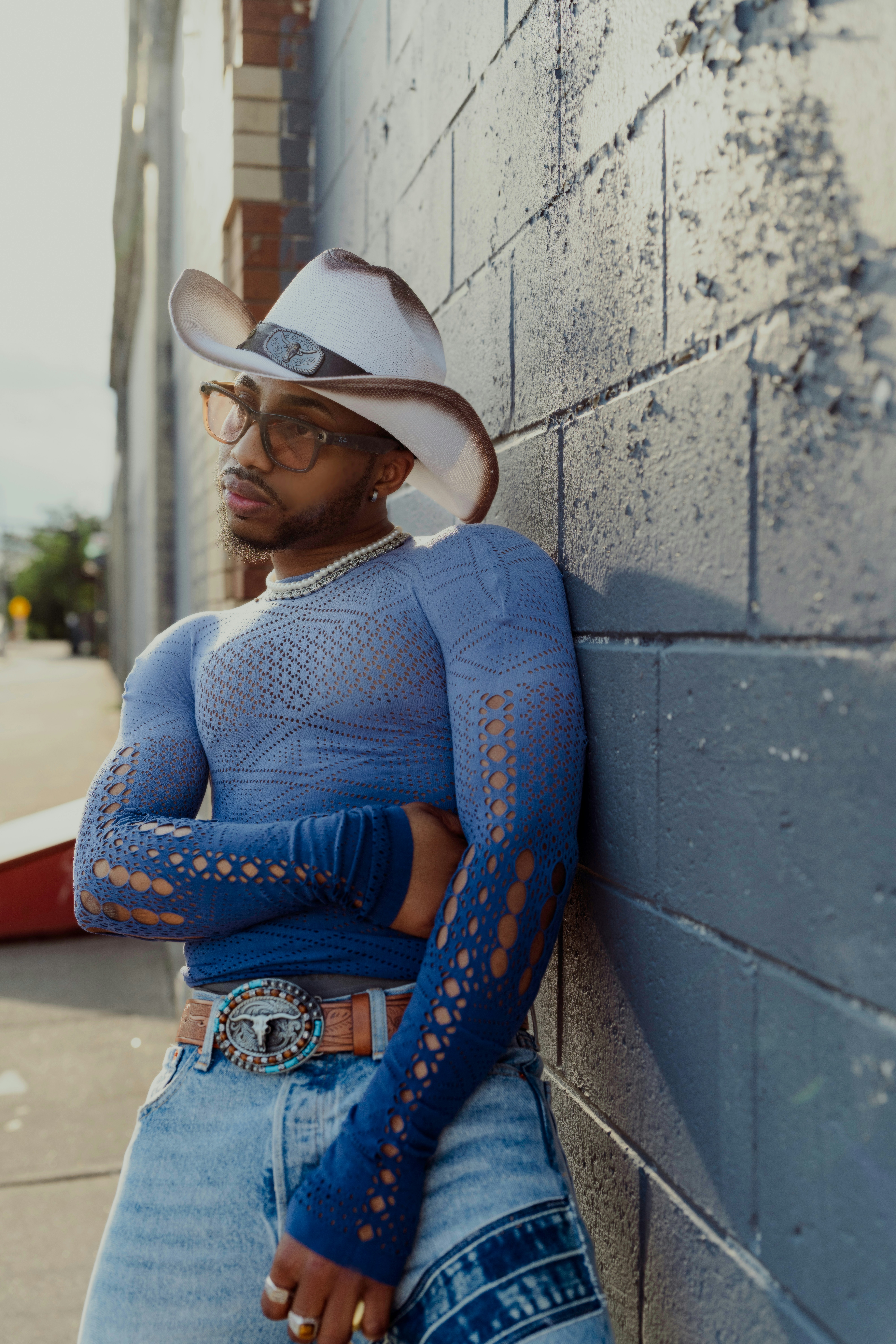 A stylish person leans against a wall.