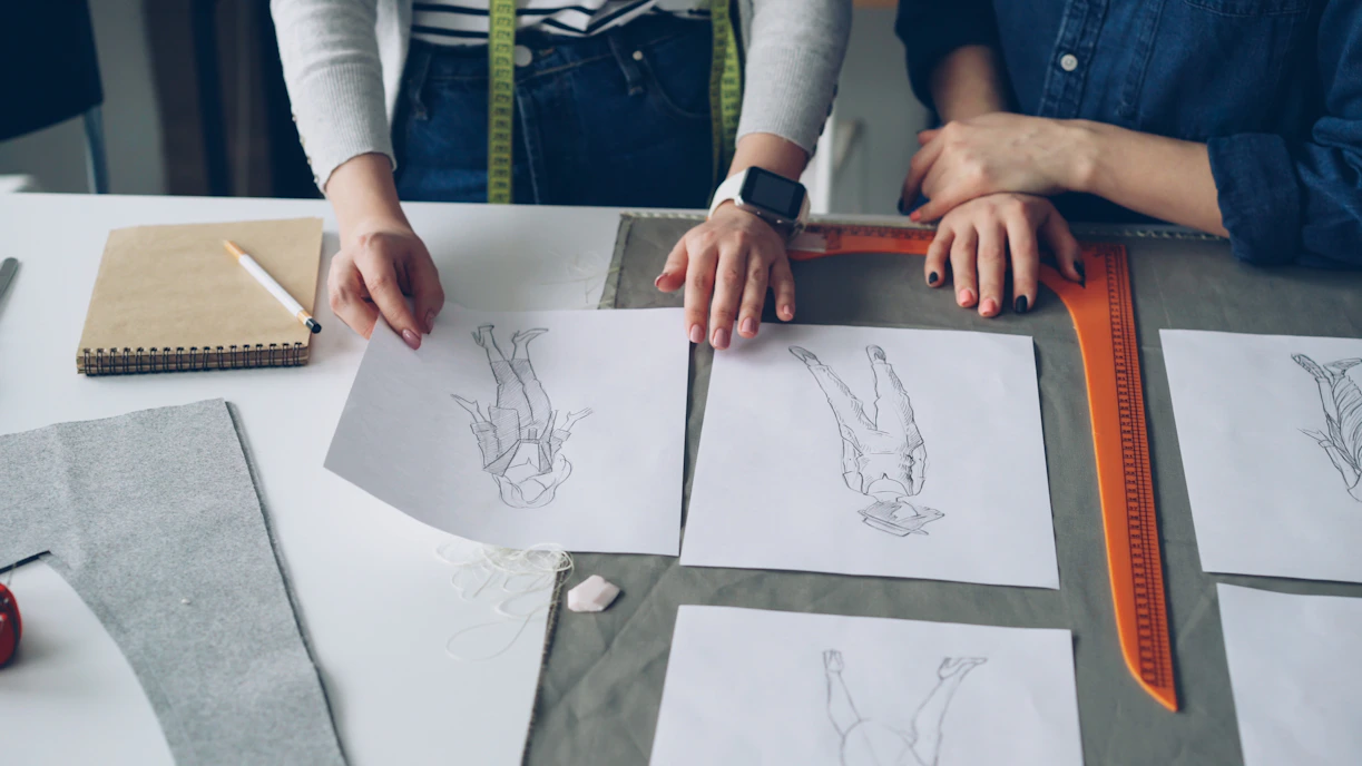 Designers look at sketches and fabrics.