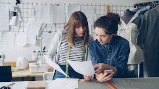 Two designers discuss a paper in a workshop.