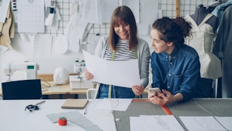 Two fashion designers review a clothing pattern.