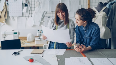 Two fashion designers review a clothing pattern.
