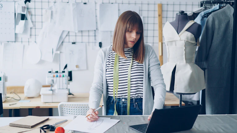 A fashion designer works at a laptop.