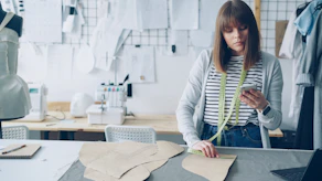 Fashion designer works on patterns in her studio.
