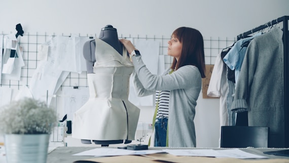 A fashion designer works on a dress form.