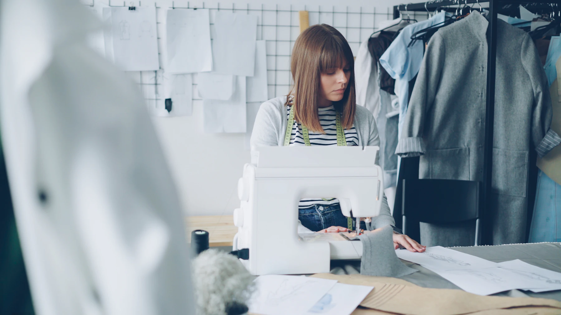 A clothing designer working on a garment at her sewing machine