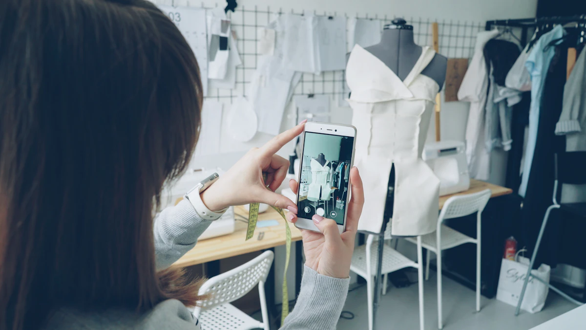 Une femme tient son téléphone à hauteur des yeux devant un buste de couture habillé, dans un atelier où des vêtements sont suspendus