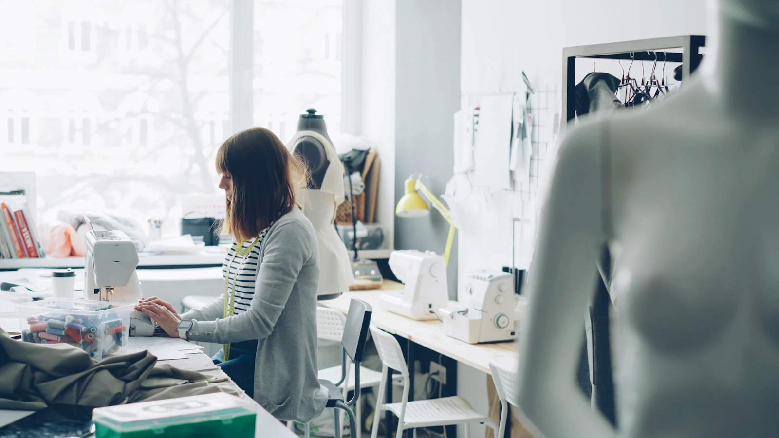 Skilled dressmaker crafting a tailored garment at her studio work station in natural light