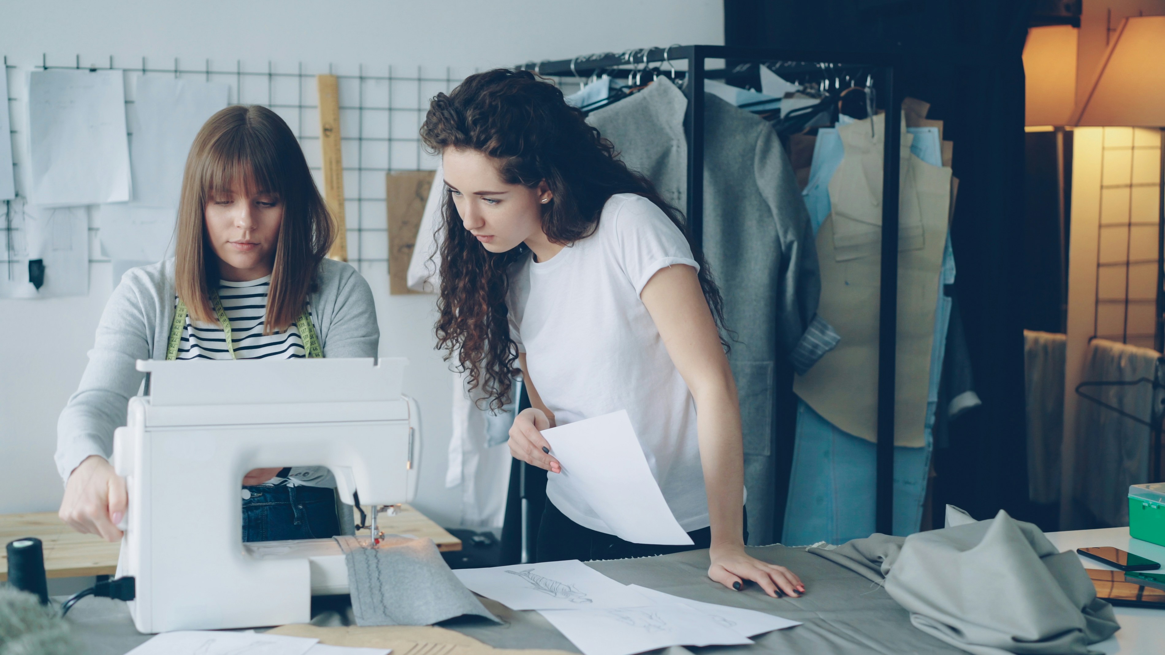 Two women working on clothes in a studio.