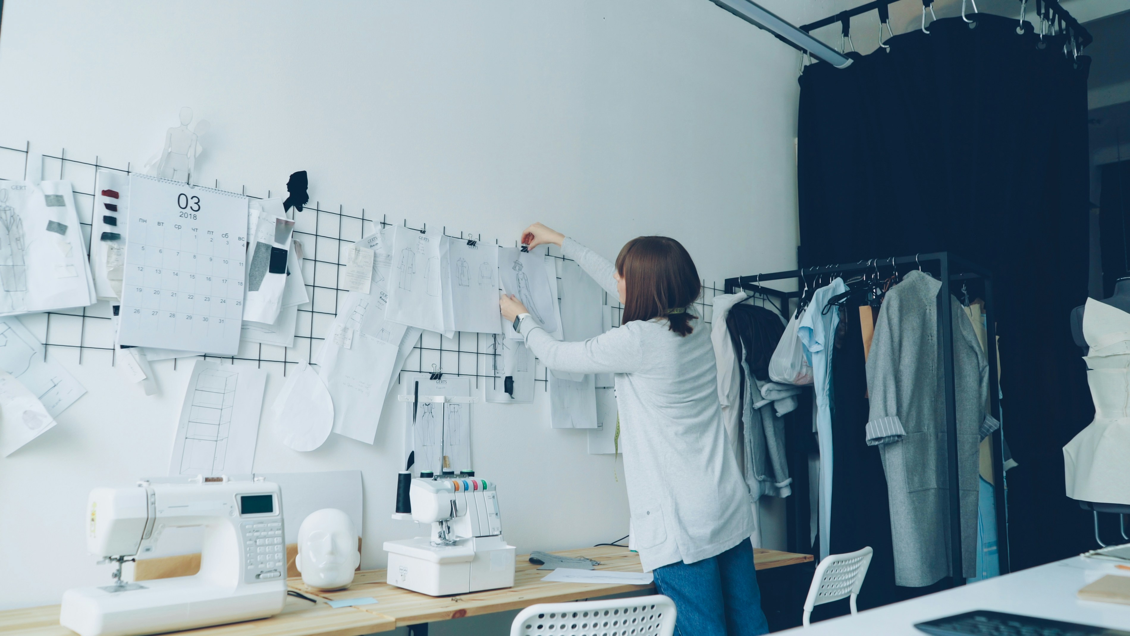 A seamstress hangs up patterns in her workshop.