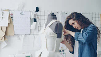 A fashion designer works on a dress form.