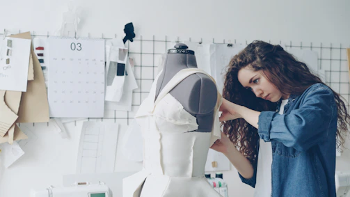 A fashion designer works on a dress form.