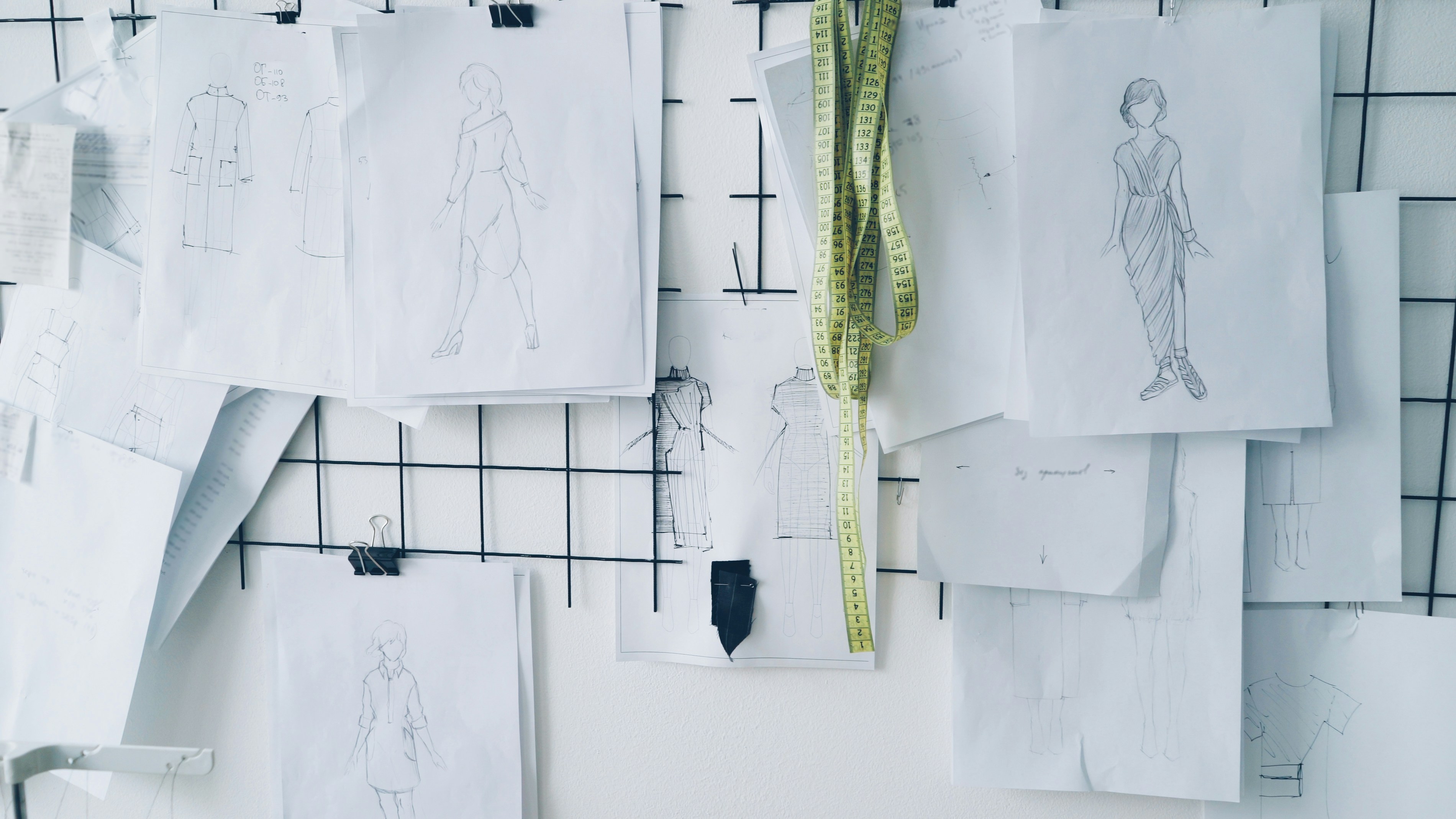Fashion sketches pinned on a grid board.