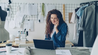 Fashion designer on the phone, working on a laptop.