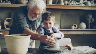 A grandfather teaches a child how to make pottery.