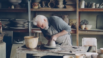 A potter molds clay on a wheel in his workshop.