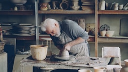 A potter molds clay on a wheel in his workshop.