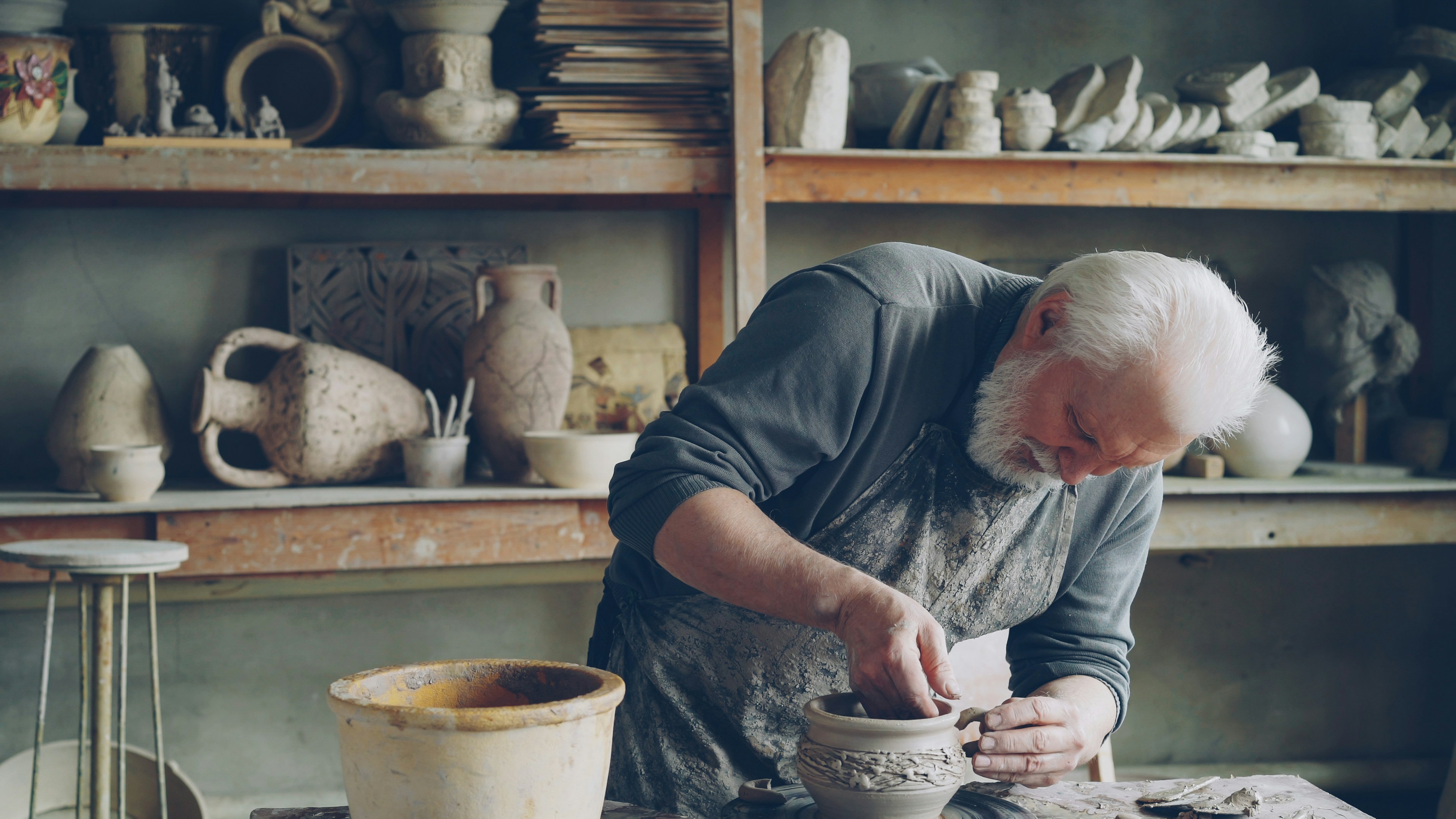 A potter works on a vase in his workshop.