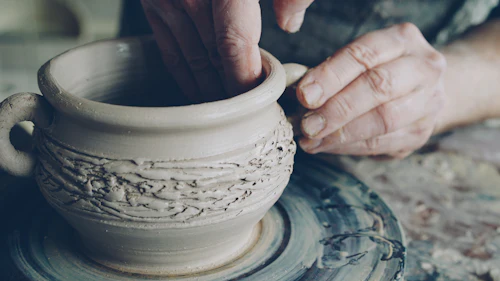 Hands throwing clay on the wheel