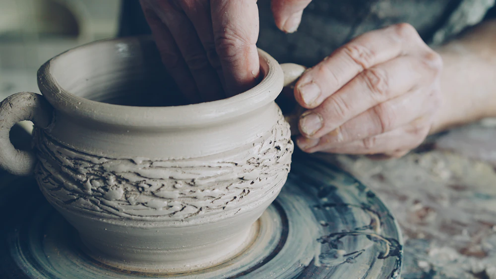 Hands shaping clay on a potter's wheel