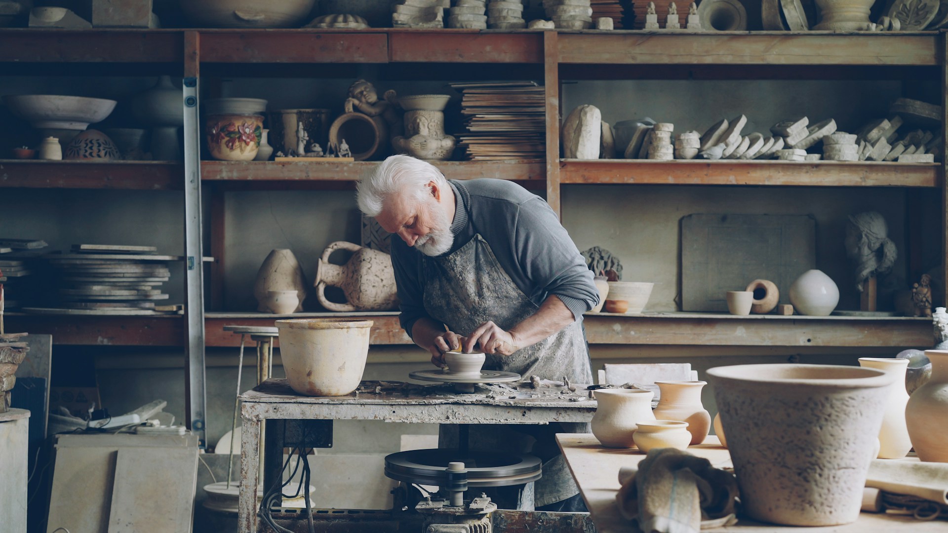 A potter works on pottery in his workshop.