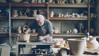 A potter works at his wheel in a workshop.