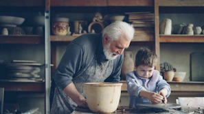 A grandfather teaches a boy pottery
