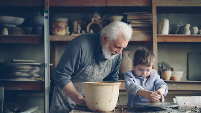A grandfather teaches a boy pottery