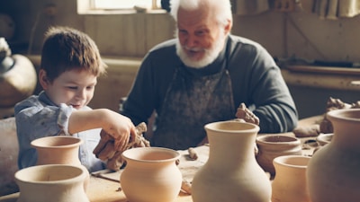A grandfather teaches his grandson pottery.