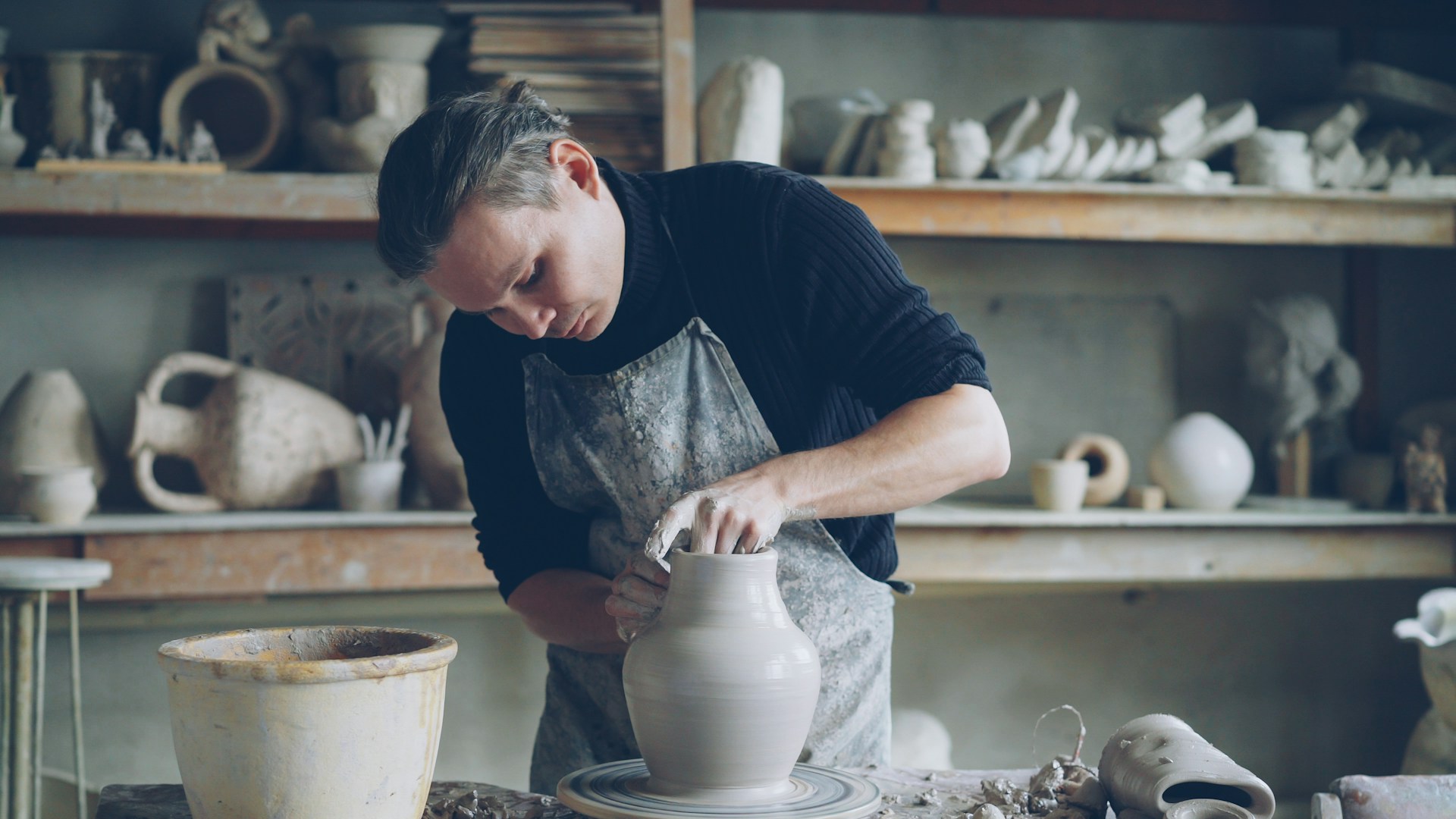 A potter is shaping a clay vase on a wheel.