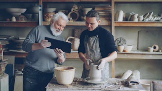 Potter guides a younger artist in his craft