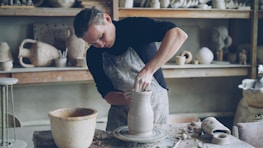 A potter works on a vase in a pottery studio.