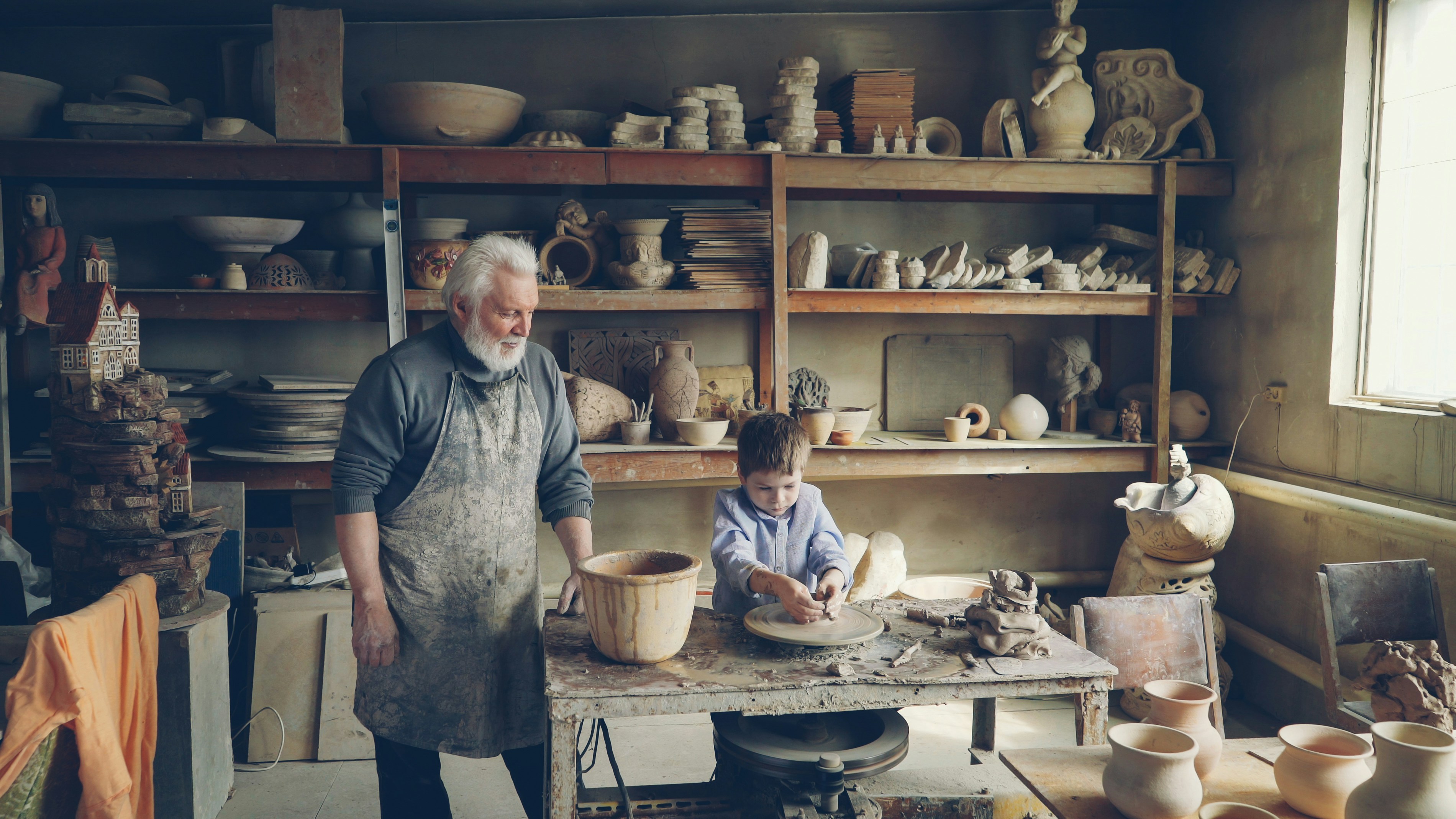 Grandfather and grandson work in a pottery studio.