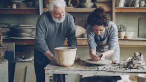 An older man and woman are working on pottery