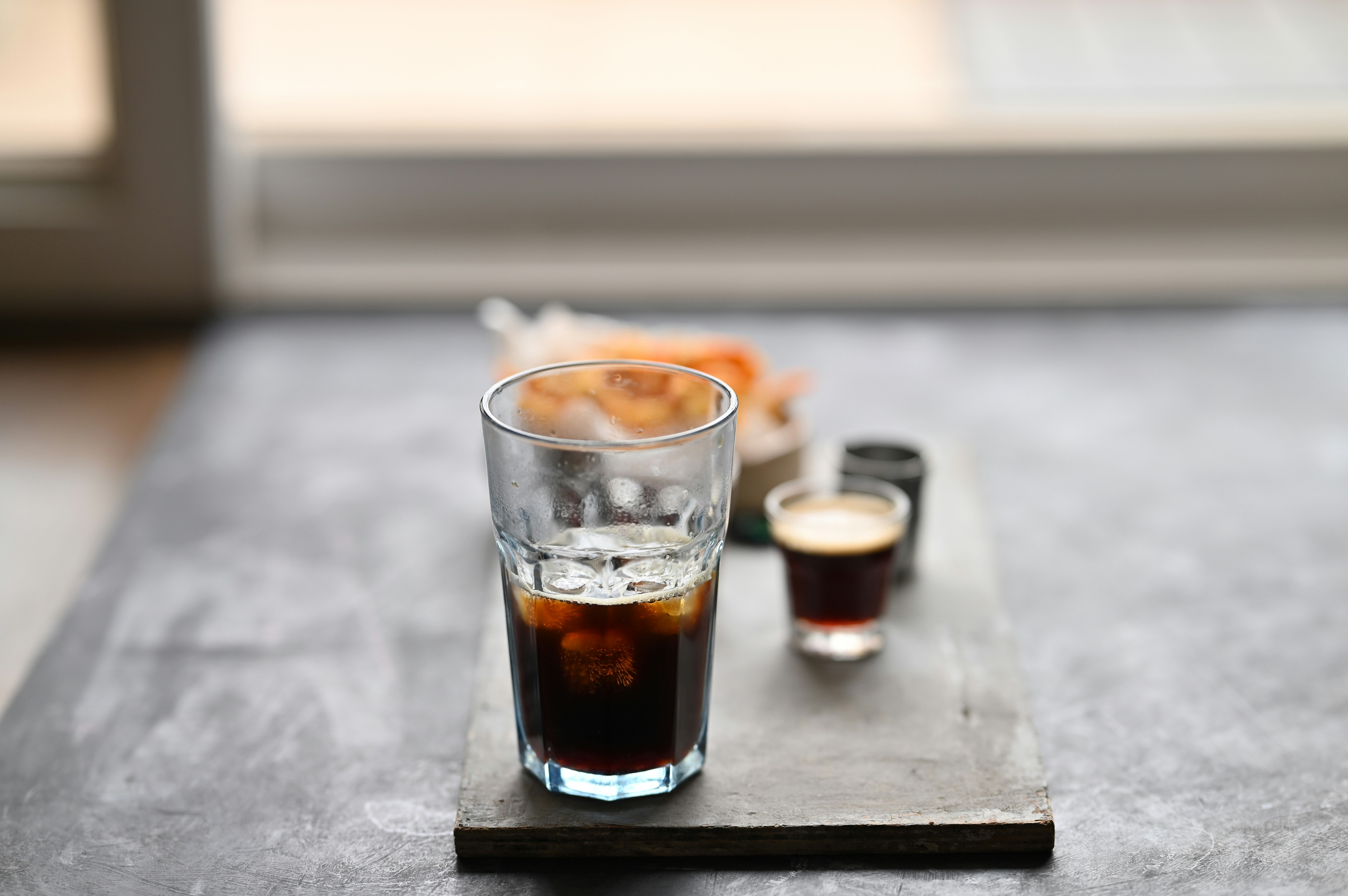 Coffee and a small shot glass sit on a table.