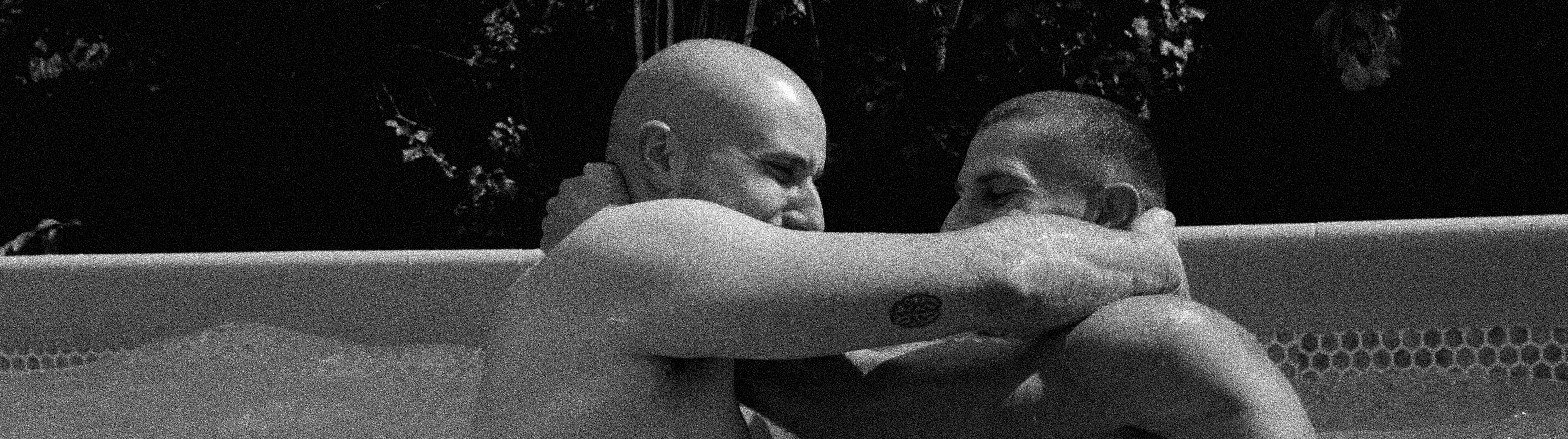 Two men are wrestling in a pool.