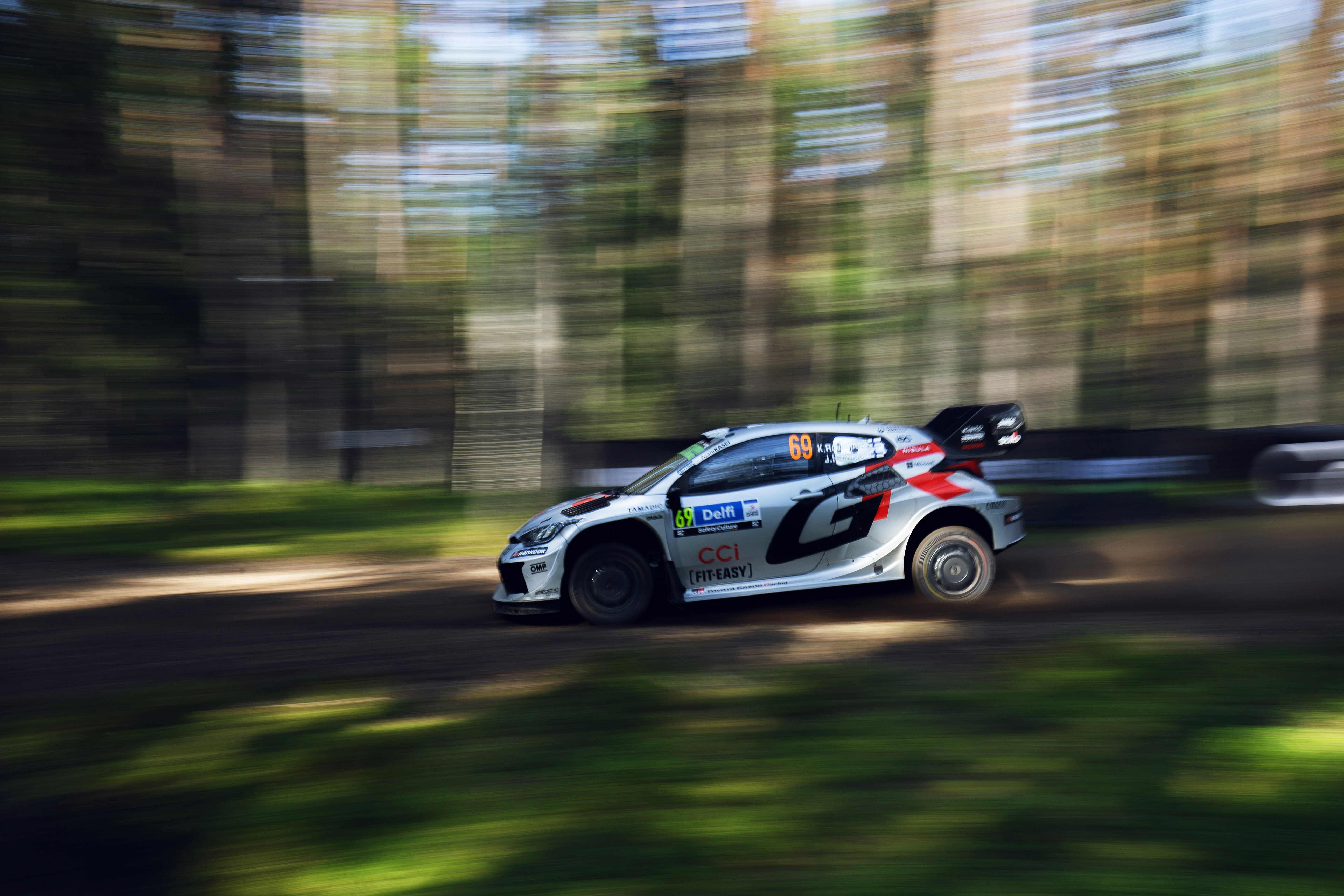 A rally car races through the forest.