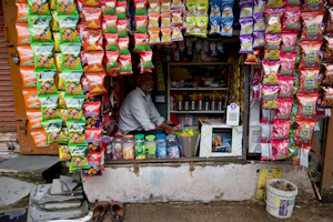 A man sells snacks and drinks at a small shop.
