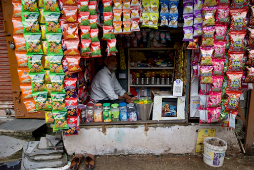 A man sells snacks and drinks at a small shop.