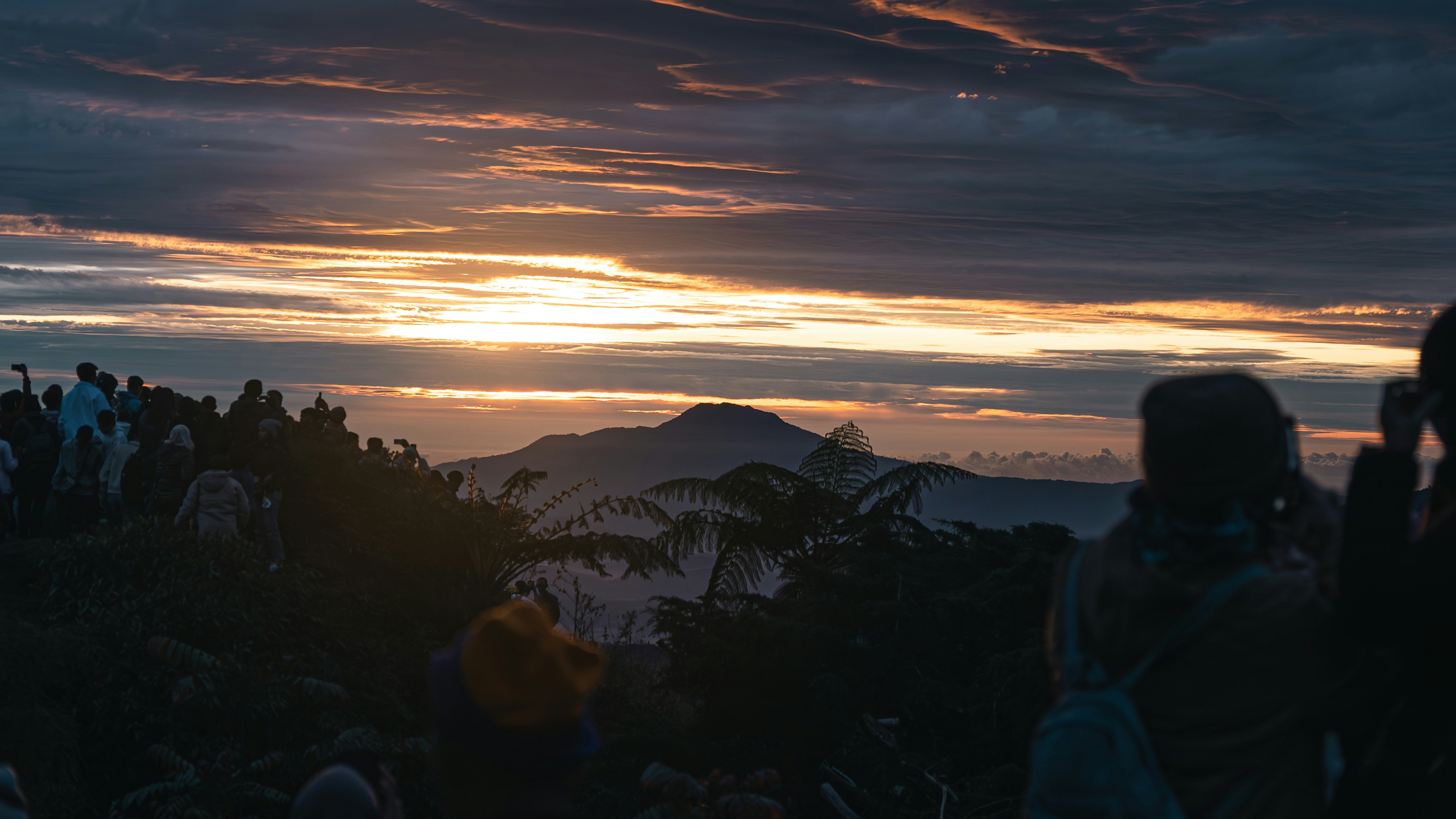 People watch a beautiful sunset over mountains.