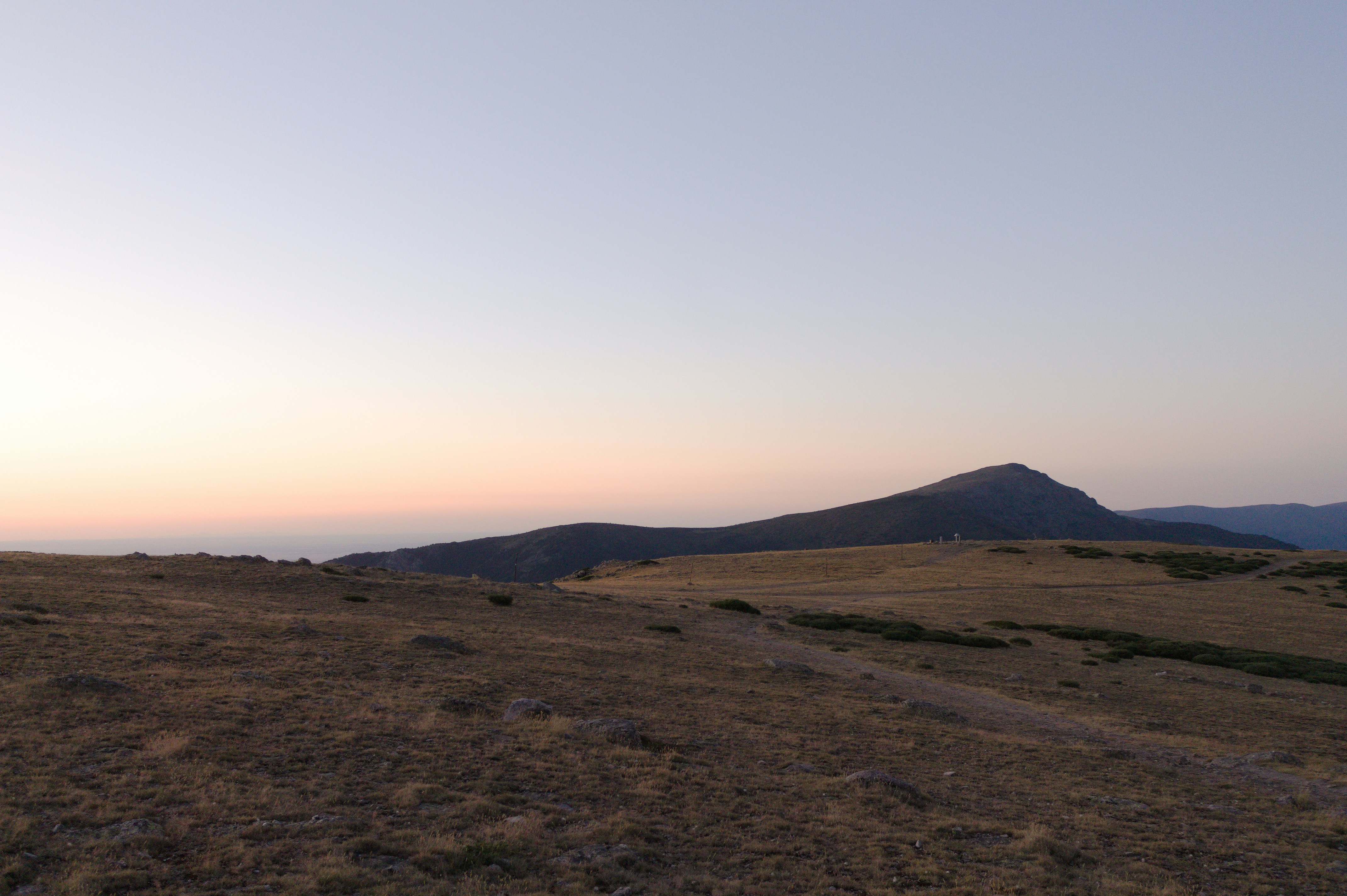 Las montañas se recortan al atardecer, con un cielo despejado.
