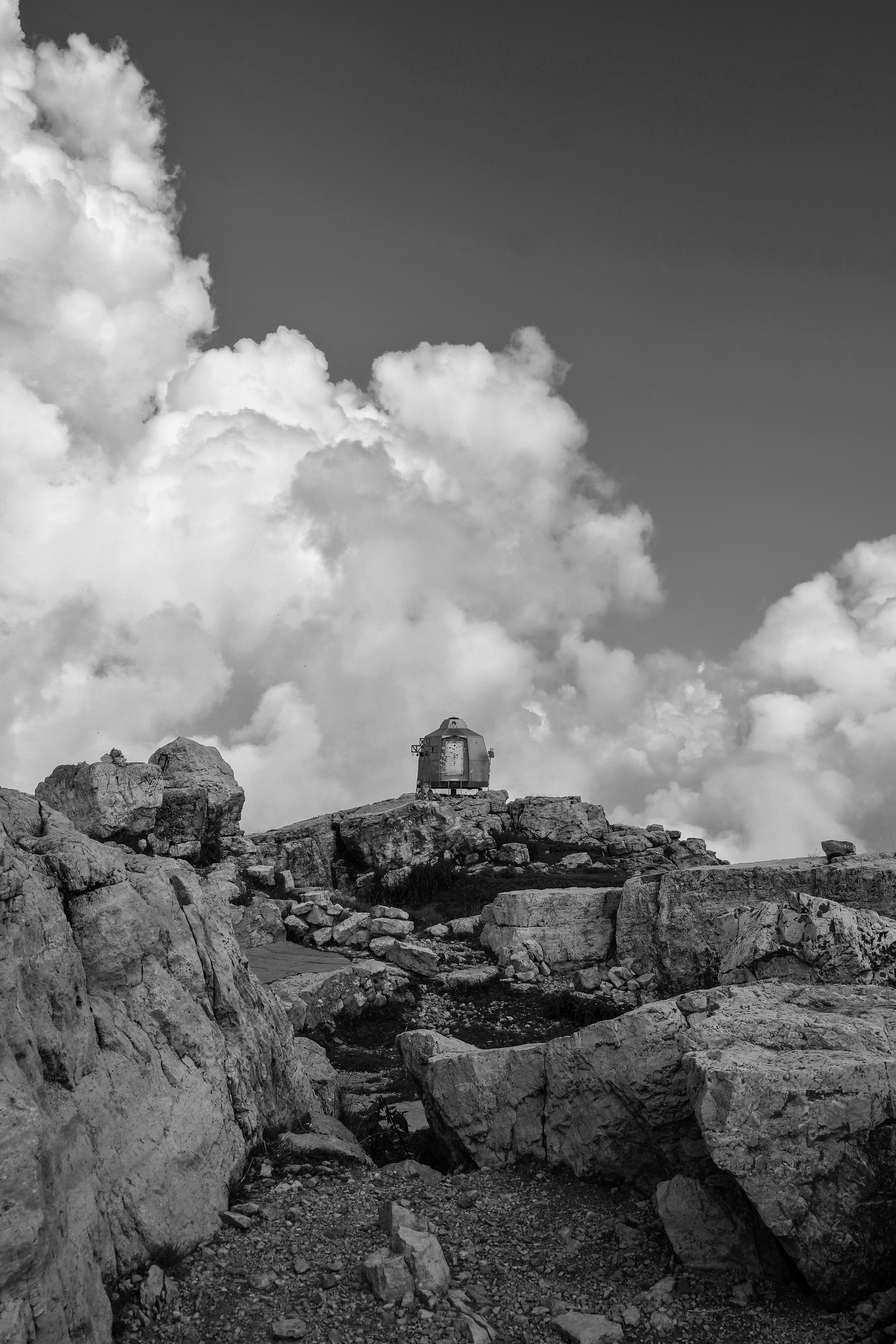 Building sits atop a rocky mountain, with cloudy skies.