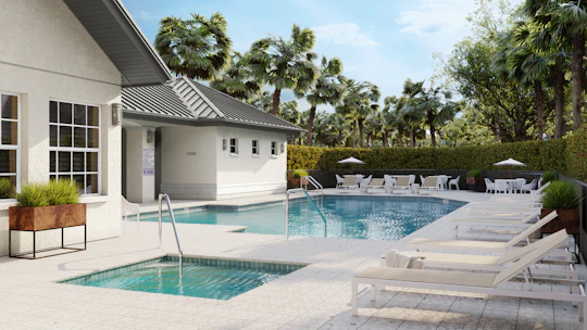 A luxurious pool area with sun loungers and building.
