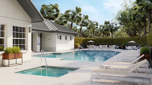 A luxurious pool area with sun loungers and building.